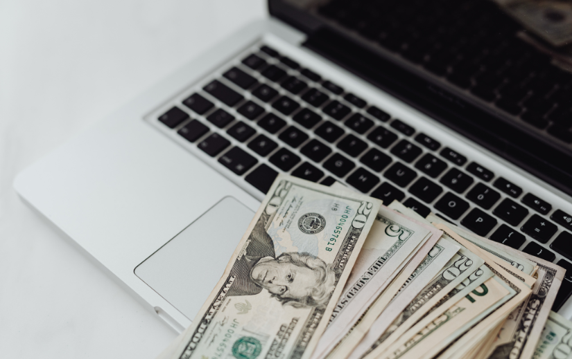 Laptop with U.S. dollar bills, symbolizing potential earnings from affiliate marketing online.